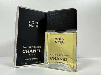 This is a product photograph of Chanel Bois Noir Eau de Toilette, showing a clear glass bottle with a large black rectangular cap containing yellow-green liquid, placed next to its black rectangular box. The box and bottle both display the text Bois Noir, Eau de Toilette, Chanel Paris, and the box indicates a size of 125 ml or 4.2 fl oz with the word Vaporisateur.