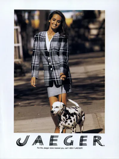 A print advertisement for Jaeger clothing brand, showing a woman with long brown hair wearing a black-and-white plaid blazer and matching mini skirt, walking a Dalmatian dog on a sidewalk. Text at the bottom reads "JAEGER" and includes a phone number: 1-800-7-JAEGER.