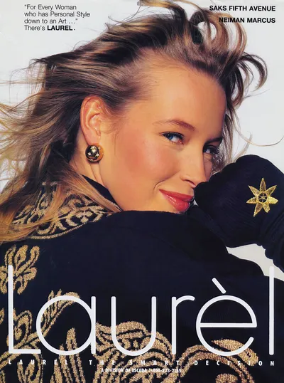 This is a vintage fashion advertisement for the brand Laurèl, described as a division of Escada, available at Saks Fifth Avenue and Neiman Marcus. It features a close-up portrait of a woman with long tousled blonde-brown hair, blue eyes, and red lips, wearing a black knit sweater or jacket with gold floral and scrollwork embroidery, and a large round gold clip-on earring with star details. She is looking over her shoulder toward the camera and smiling slightly.