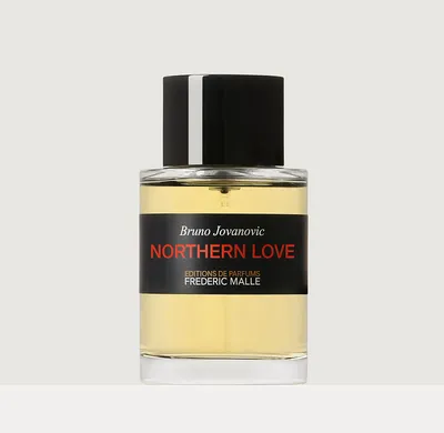 Product photograph of a glass perfume bottle with a pale yellow liquid inside and a large black cylindrical cap. The black label reads Bruno Jovanovic, Northern Love in red lettering, and Editions de Parfums Frederic Malle in white lettering.