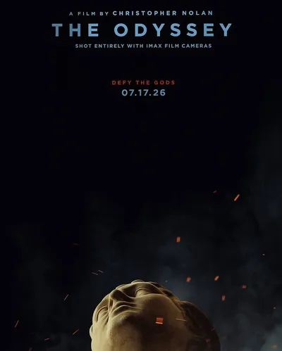 Movie poster for The Odyssey, directed by Christopher Nolan, releasing July 17, 2026, shot entirely with IMAX film cameras, with the tagline "Defy the Gods." The poster features a classical marble-style stone bust of a head tilted upward against a dark background, surrounded by glowing orange embers and wisps of smoke.
