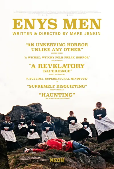 This is a movie poster for Enys Men, written and directed by Mark Jenkin, distributed by Neon. The poster shows a person in a red jacket and jeans lying face-down on rocky ground, surrounded by a group of figures dressed in dark period clothing with white aprons and bonnets who are standing and sitting on the rocks looking down at them.